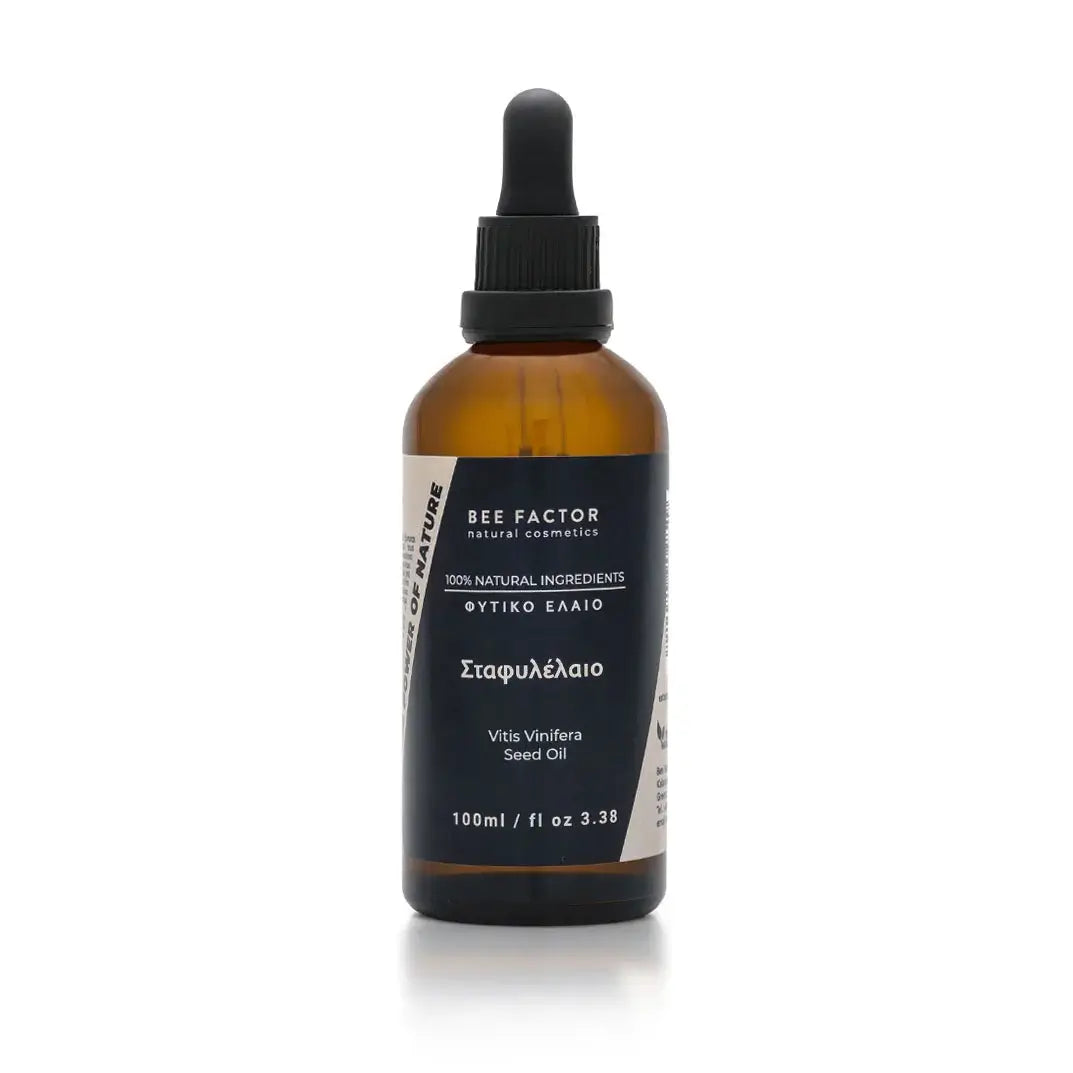 Το σταφυλέλαιο της Bee Factor Natural Cosmetics σε κεχριμπαρένια γυάλινη φιάλη 100 ml με μαύρο σταγονόμετρο, σχεδιασμένο με minimal και επαγγελματική αισθητική. Στην μπροστινή ετικέτα διακρίνονται το λογότυπο “Bee Factor natural cosmetics”, η ένδειξη “100% natural ingredients”, η κατηγορία «φυτικό έλαιο», η ονομασία «Σταφυλέλαιο» και η λατινική ονομασία “Vitis Vinifera Seed Oil”. Το προϊόν απεικονίζεται μετωπικά, μόνο του, σε καθαρό ανοιχτόχρωμο φόντο, αποπνέοντας αίσθηση φυσικότητας, καθαρότητας και στοχευ