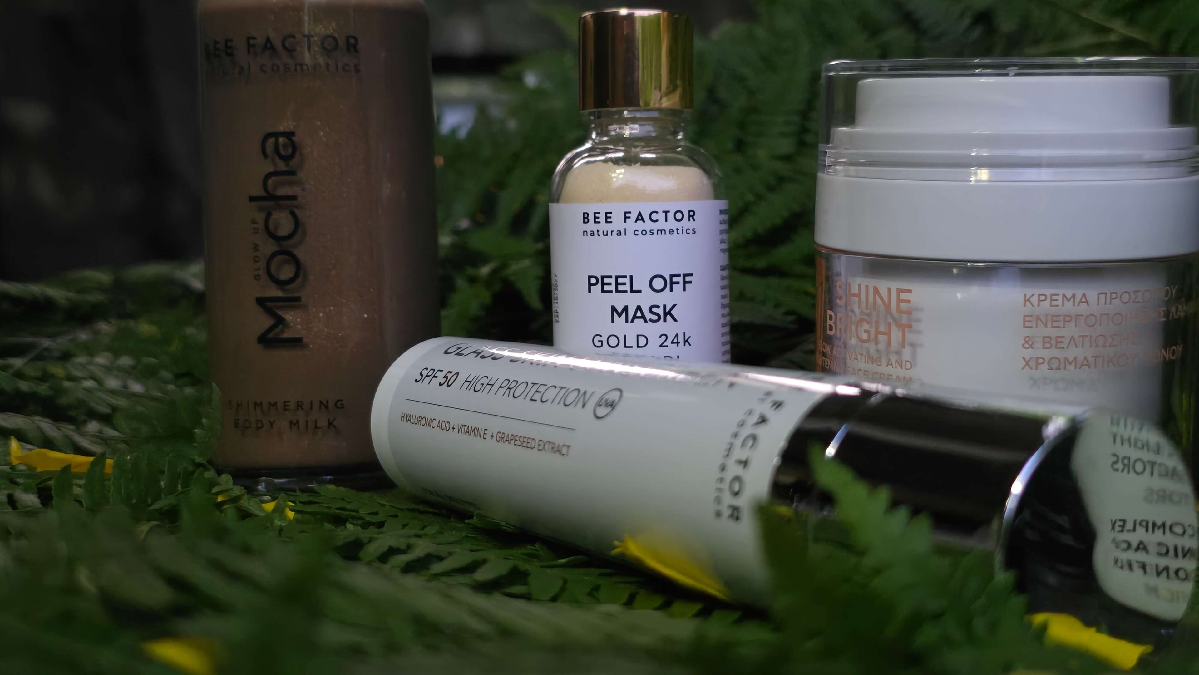 Προϊόντα Bee Factor σε φυσικό σκηνικό: shimmering body milk Mocha, peel-off mask Gold 24k, κρέμα προσώπου Shine Bright και αντηλιακή προστασία προσώπου SPF50 – διαθέσιμα στο Eiria Cosmetics