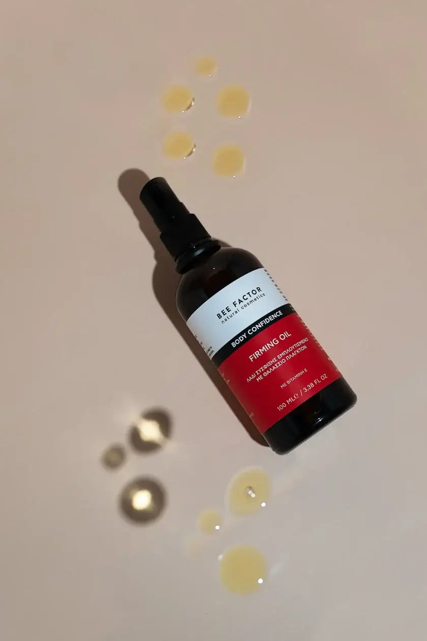 Bee Factor Firming Oil 100ml – φυσικό λάδι σύσφιξης με βιταμίνη Ε και θαλάσσιο πλαγκτόν, φωτογραφημένο με σταγόνες προϊόντος σε nude φόντο, διαθέσιμο στο eiria.gr για τόνωση και μείωση κυτταρίτιδας.