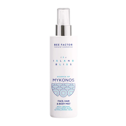 Το Essence of Mykonos Face, Hair & Body Mist της συλλογής The Island Bliss από τη Bee Factor Natural Cosmetics, σε λευκή φιάλη spray με διάφανο καπάκι και ασημί λεπτομέρεια στο επάνω μέρος. Στην μπροστινή όψη διακρίνονται το λογότυπο “Bee Factor natural cosmetics”, η ονομασία της σειράς “The Island Bliss”, η ένδειξη “Essence of Mykonos” και η κατηγορία “Face, Hair & Body Mist”, μαζί με αναφορά σε organic cultivated aloe και hyaluronic acid. Το μπλε διακοσμητικό μοτίβο στο κάτω μέρος της ετικέτας παραπέμπει 