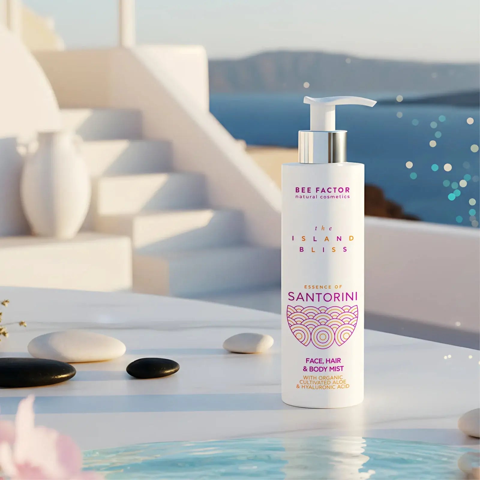 Μια όμορφη εικόνα του Essence of Santorini Face, Hair & Body Mist από τη Bee Factor Natural Cosmetics. Η λευκή φιάλη με αντλία στέκεται σε μια λευκή επιφάνεια, μπροστά σε ένα φόντο που θυμίζει μια κυκλαδίτικη αυλή με θέα στη θάλασσα. Στη φιάλη, διακρίνονται το λογότυπο της Bee Factor Natural Cosmetics, η ονομασία της σειράς The Island Bliss, η ένδειξη Essence of Santorini και η κατηγορία Face, Hair & Body Mist. Επίσης, υπάρχει αναφορά σε organic cultivated aloe και hyaluronic acid. Γύρω από το προϊόν, υπάρχ