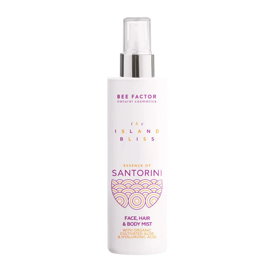 Το Essence of Santorini Face, Hair & Body Mist της συλλογής The Island Bliss από τη Bee Factor Natural Cosmetics, σε λευκή φιάλη spray με διάφανο καπάκι και ασημί λεπτομέρεια στο επάνω μέρος. Στην μπροστινή όψη διακρίνονται το λογότυπο “Bee Factor natural cosmetics”, η ονομασία της σειράς “The Island Bliss”, η ένδειξη “Essence of Santorini” και η κατηγορία “Face, Hair & Body Mist”, μαζί με αναφορά σε organic cultivated aloe και hyaluronic acid. Το διακοσμητικό μοτίβο στο κάτω μέρος της ετικέτας, σε μωβ και 
