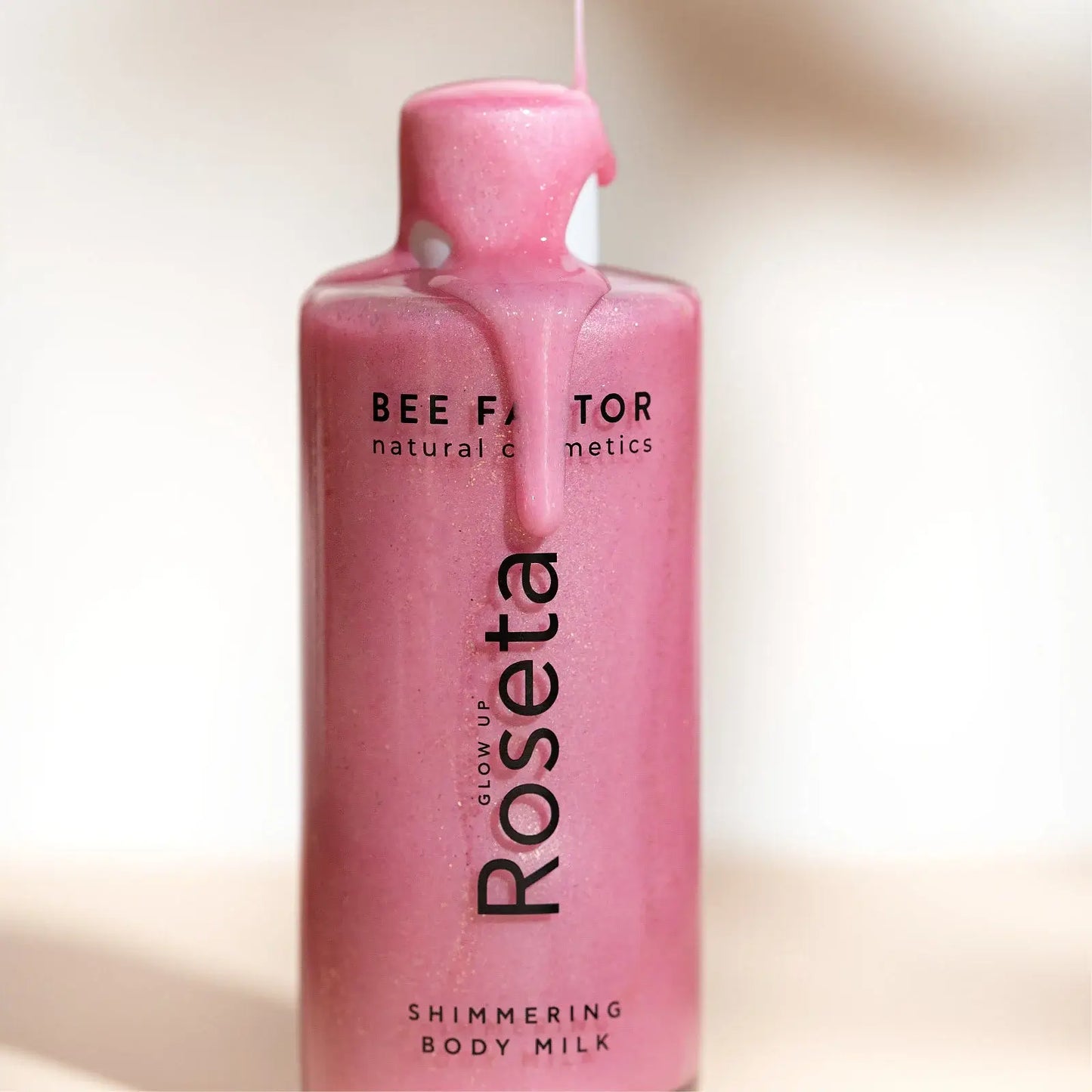 Glow Up Roseta Shimmering Body Milk 100ml της Bee Factor, το προϊόν χύνεται στη συσκευασία.