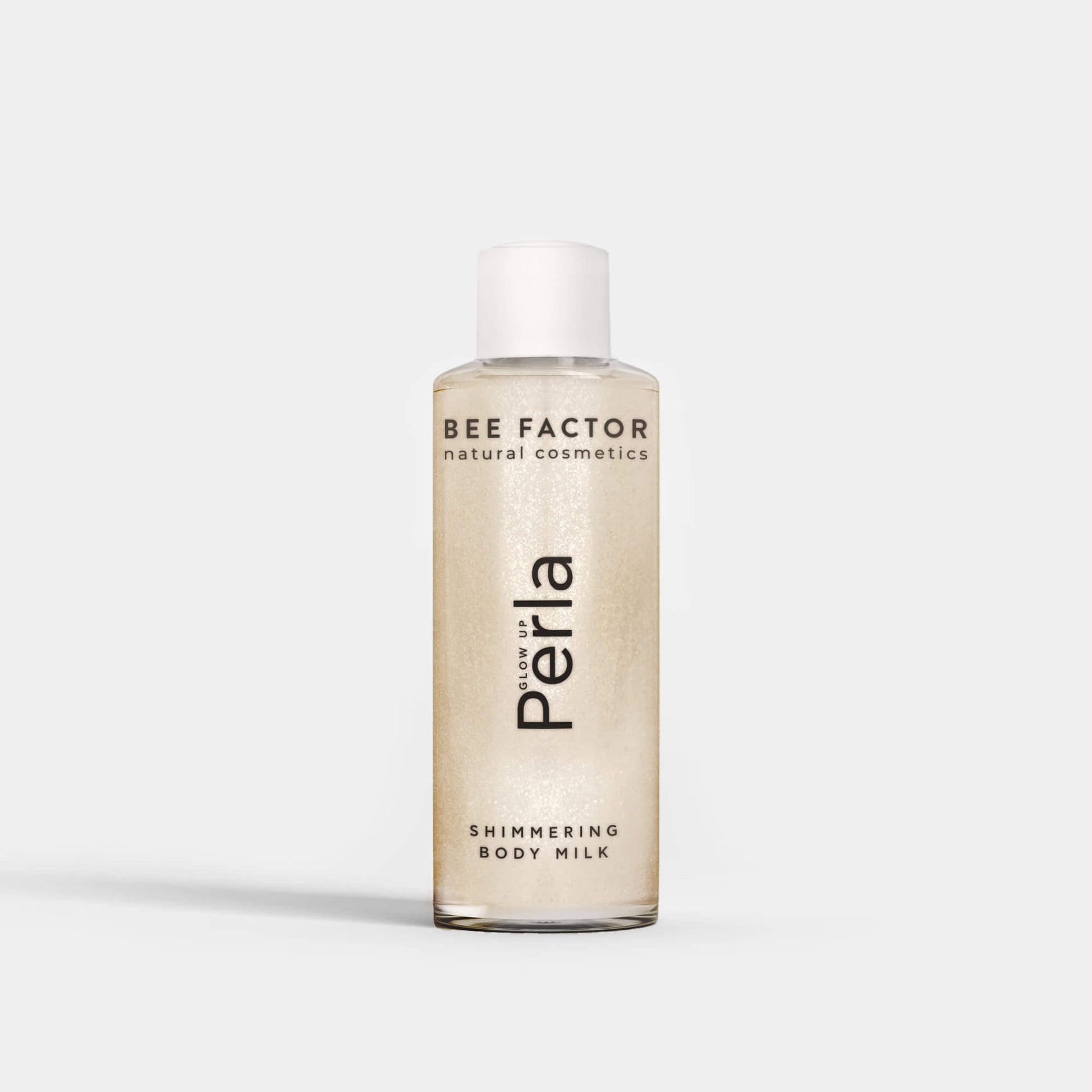 Το Glow Up Perla Shimmering Body Milk της Bee Factor σε διάφανη φιάλη 100 ml με λευκό καπάκι, που αναδεικνύει τη λαμπερή περλέ σύνθεση του προϊόντος. Στην μπροστινή όψη εμφανίζονται το λογότυπο “Bee Factor natural cosmetics”, η ονομασία “Perla” και η ένδειξη “Shimmering Body Milk”. Το προϊόν απεικονίζεται μετωπικά, μόνο του, σε καθαρό ανοιχτόχρωμο φόντο, αποπνέοντας αίσθηση κομψότητας, λάμψης και περιποίησης σώματος.
