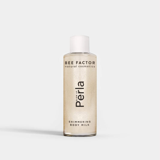 Το Glow Up Perla Shimmering Body Milk της Bee Factor σε διάφανη φιάλη 100 ml με λευκό καπάκι, που αναδεικνύει τη λαμπερή περλέ σύνθεση του προϊόντος. Στην μπροστινή όψη εμφανίζονται το λογότυπο “Bee Factor natural cosmetics”, η ονομασία “Perla” και η ένδειξη “Shimmering Body Milk”. Το προϊόν απεικονίζεται μετωπικά, μόνο του, σε καθαρό ανοιχτόχρωμο φόντο, αποπνέοντας αίσθηση κομψότητας, λάμψης και περιποίησης σώματος.