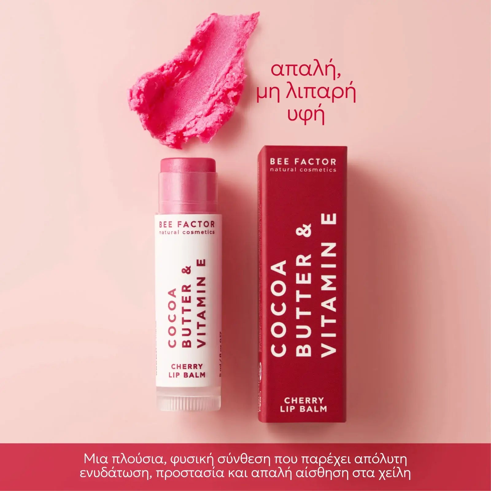 Bee Factor cherry lip balm (ενυδατικό βάλσαμο χειλιών με γεύση κεράσι) με βούτυρο κακάο & βιταμίνη E, με τη συσκευασία δίπλα και δείγμα της ροζ υφής του πάνω σε ροζ φόντο με μήνυμα «απαλή, μη λιπαρή υφή» – Eiria.gr