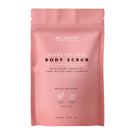 Το Sugar Feelings Body Scrub της Bee Factor Natural Cosmetics σε ροζ ματ συσκευασία τύπου pouch με επανακλειόμενο κλείσιμο, σχεδιασμένη με minimal και μοντέρνα αισθητική. Στην μπροστινή όψη αναγράφονται η ονομασία του προϊόντος, η σύνθεσή του με κόκκους ζάχαρης, βούτυρο καριτέ και βιταμίνη Ε, καθώς και ότι απολεπίζει και καθαρίζει αφήνοντας την επιδερμίδα λεία και απαλή. Η συσκευασία τονίζει επίσης ότι το προϊόν είναι 98,5% φυσικό, εμπλουτισμένο με αμυγδαλέλαιο και έλαιο αβοκάντο, ενώ στο κάτω μέρος αναφέρε